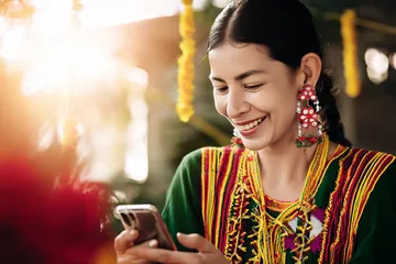 A cheerful woman in traditional clothing using her smartphone during a festive moment, showing how easily the F7 F7 app fits into everyday life.